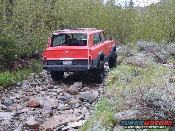 Red SUV with roof rack on rocky trail, license plate AL 8341