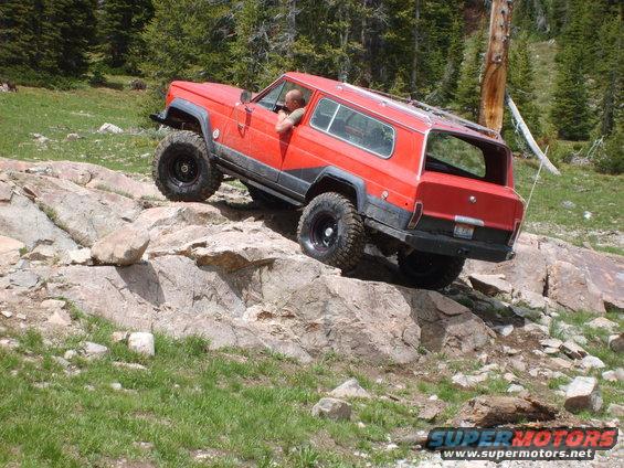 Red Jeep Cherokee Chief off-roading on rocks