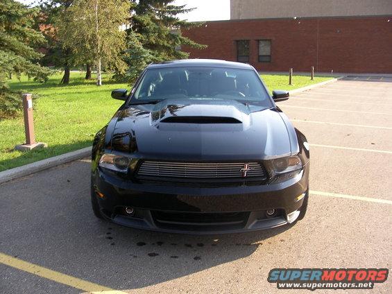 Front view of a black 2010 Ford Mustang with a prominent hood scoop and chrome grille