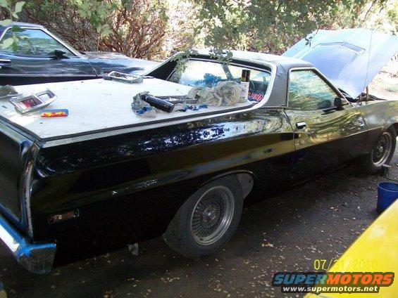 Black 1972 Ford Ranchero with hood open, tail lights on bed, and tools on cover