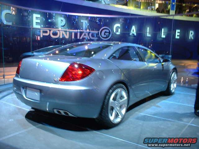 Silver concept car with large taillights and dual exhaust tips on display at an auto show