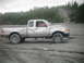 1993 Suzuki Sidekick - Silver pickup truck with significant front-end damage sits on a dirt lot with trees in the background.