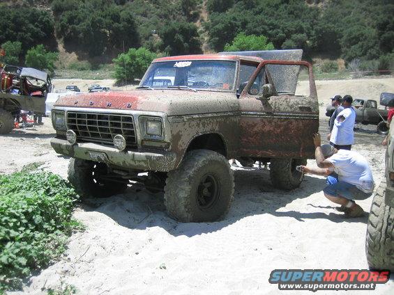 Muddy old Ford SUV with door open, someone taking a photo