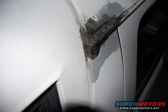 Close-up of a welded metal seam on a white vehicle, showing repair work
