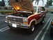 1986 Ford Bronco - The front end of a classic Ford Bronco is visible with its hood raised, revealing the engine compartment.