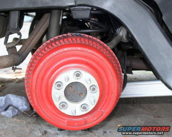 Close-up of a red painted wheel with visible lug nuts and suspension components