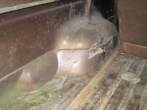 Brown interior of a dusty vehicle, showing wheel well and ribbed floor