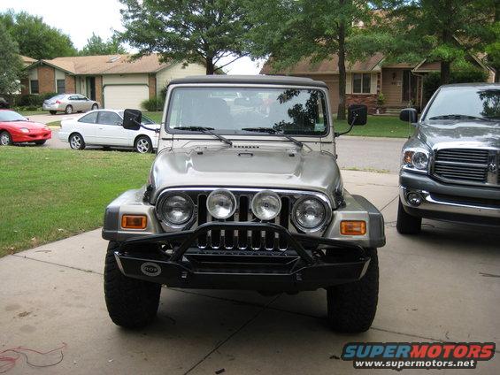 Silver Jeep Wrangler front view with aftermarket bumper and auxiliary lights