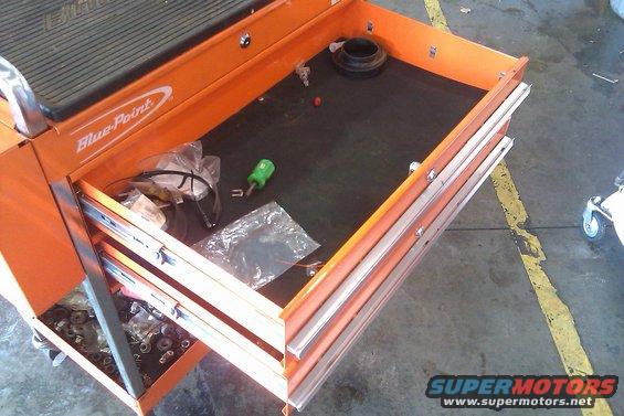 Orange Blue-Point tool cart with open drawers containing tools and parts. A green screwdriver is visible
