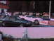 1992 Ford Mustang - Two cars are lined up at a drag strip, ready for a race. The dark green car is in the foreground.