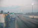 1992 Ford Mustang - A red 1992 Ford Mustang competes on a drag strip under hazy skies, with spectators in the background.