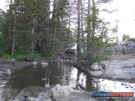 Silver off-road vehicle navigating a rocky stream bed
