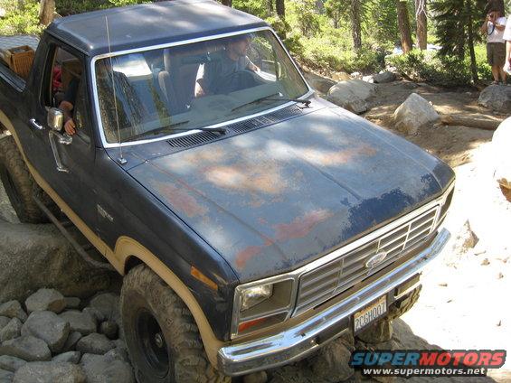 Dark blue Ford Bronco with rusty hood on rocky terrain