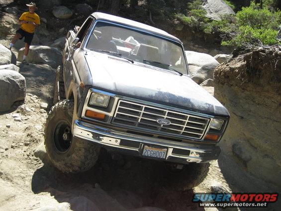 Ford F-Series truck going off-road over rocks. Guy in yellow shirt watching