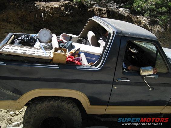 1986 Ford Bronco side view, dark blue with tan trim, loaded with gear