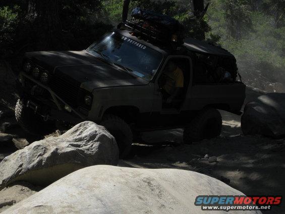 Modified off-road SUV with roof rack navigating a rocky trail. "GO PREPARED" sticker on windshield