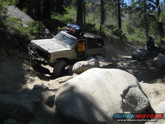 Off-road SUV navigating a boulder-strewn trail in a forest