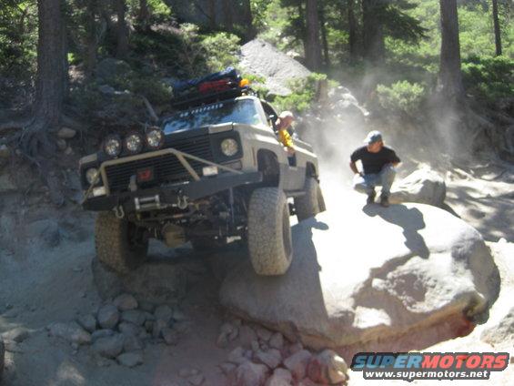 Off-road vehicle with custom bumper and lights climbing rocks