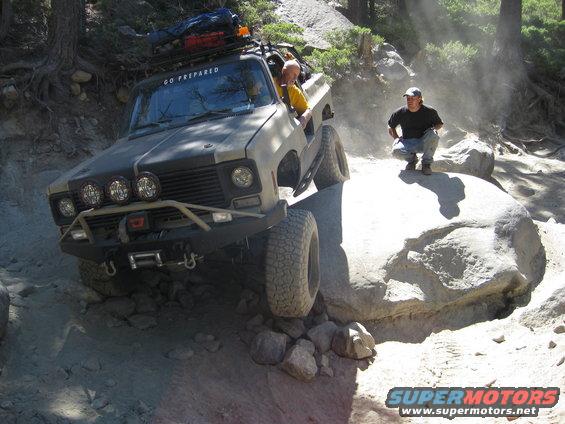 Modified 1973 Chevrolet K5 Blazer off-roading on a dirt trail with large rocks