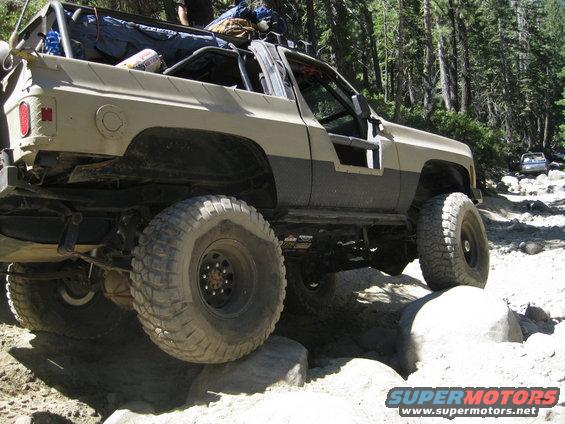 Tan and gray off-road SUV with large tires navigating rocky terrain
