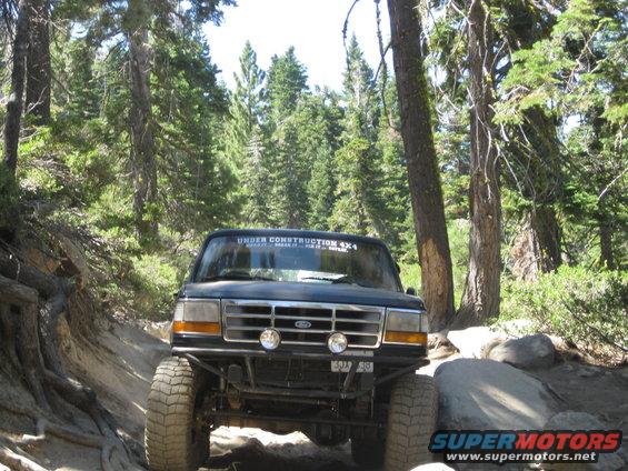 Dark blue Ford Bronco with off-road modifications on a rocky trail