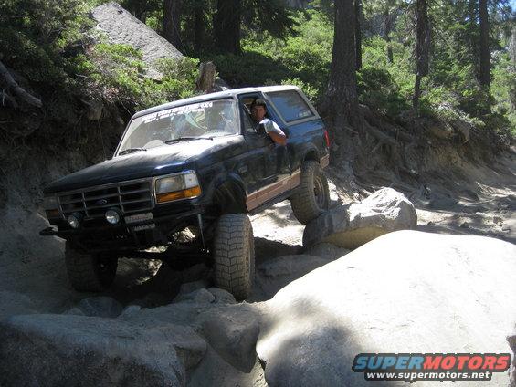 Black Ford Bronco with lifted suspension navigating a boulder-strewn trail