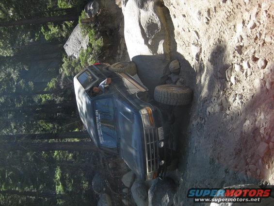 Dark blue 1987 Ford Bronco tilted on a rocky trail, front grille visible