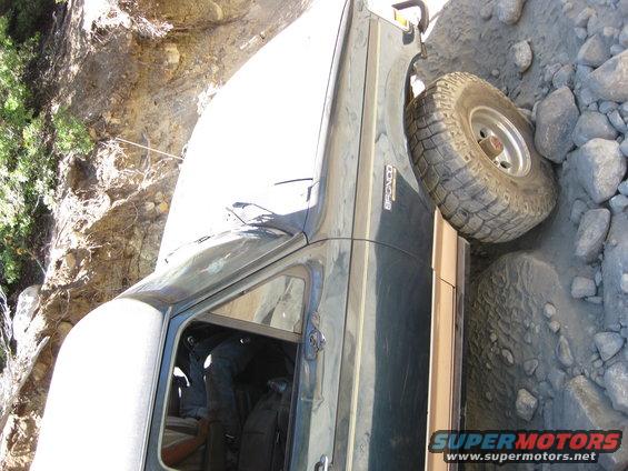 Dark green Ford Bronco on rocky terrain, driver's side visible, off-road tire