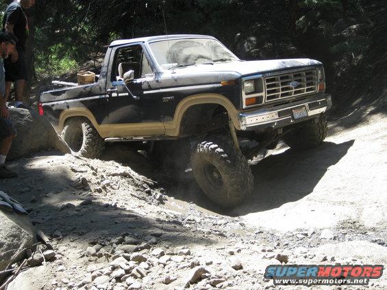 Dark blue and tan Ford Bronco off-roading on a rocky trail