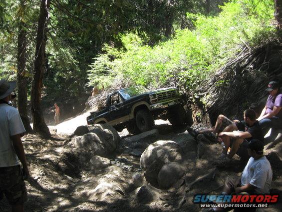 Black Ford Bronco navigating a rocky trail, front-right tire elevated