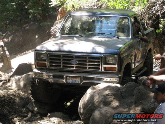 Dark blue Ford F-Series truck with a chrome grille and bumper navigating rocky terrain
