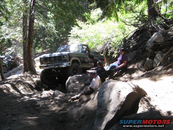 Green 1980s Ford Bronco navigating rocky terrain