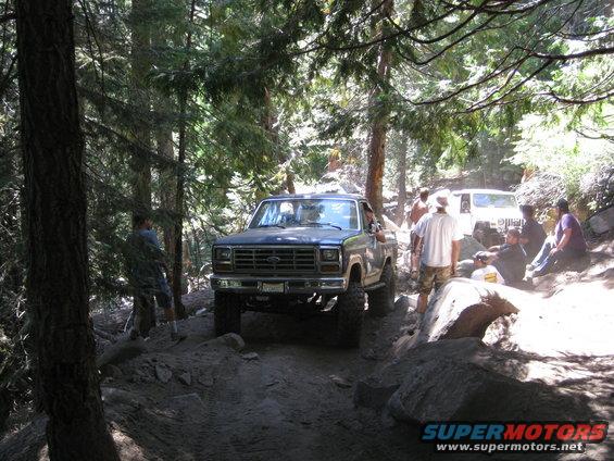 Ford F-Series pickup truck on a rocky trail with people around. Another Jeep is visible behind it