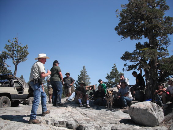Off-road vehicle parked on rocks with a group of people gathered
