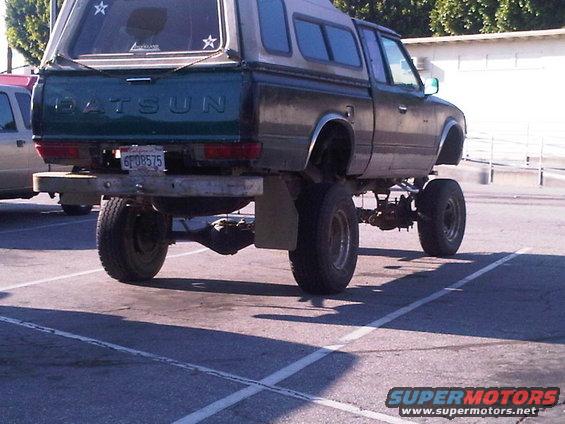 Lifted Datsun pickup truck with a camper shell, seen from the rear