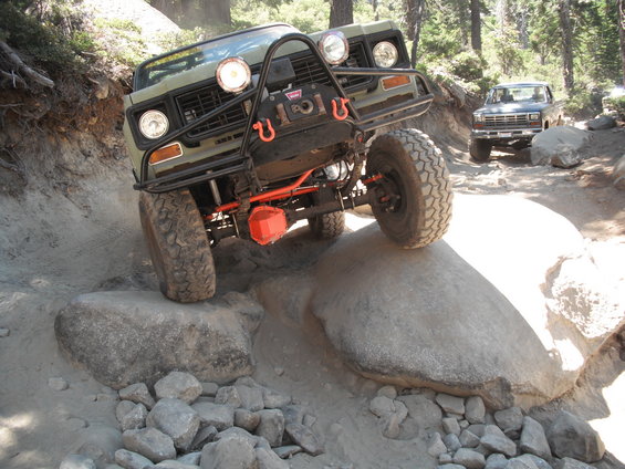 Olive green off-road vehicle with winch and bull bar navigating rocks