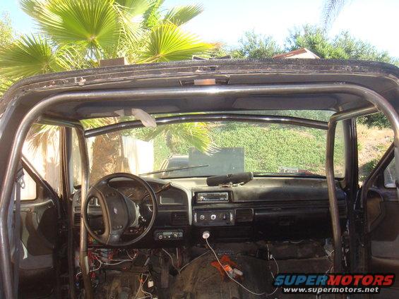Interior view of a truck with a roll cage installed. Steering wheel and dashboard are visible