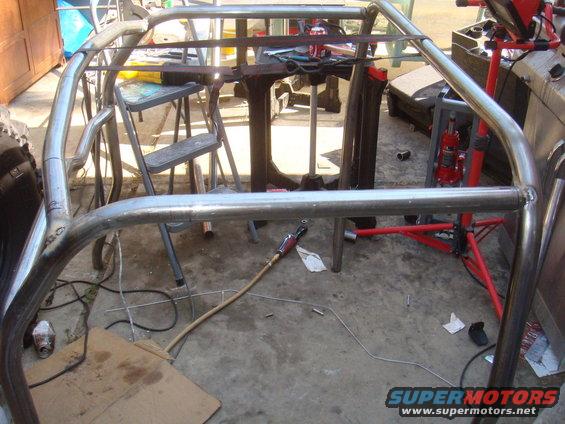 Metal roll cage frame with welding equipment and tools on concrete floor