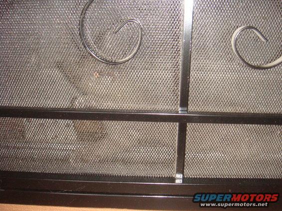 Black metal fireplace screen with decorative scrollwork and mesh