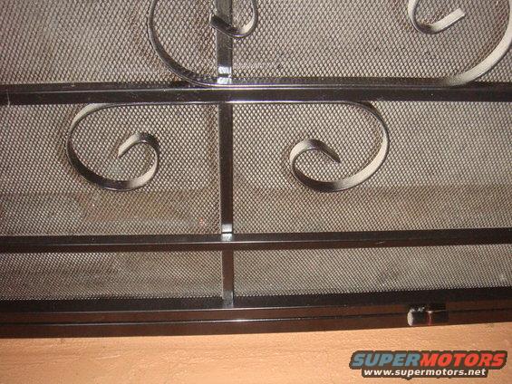 close-up of a decorative metal screen with scrollwork over mesh