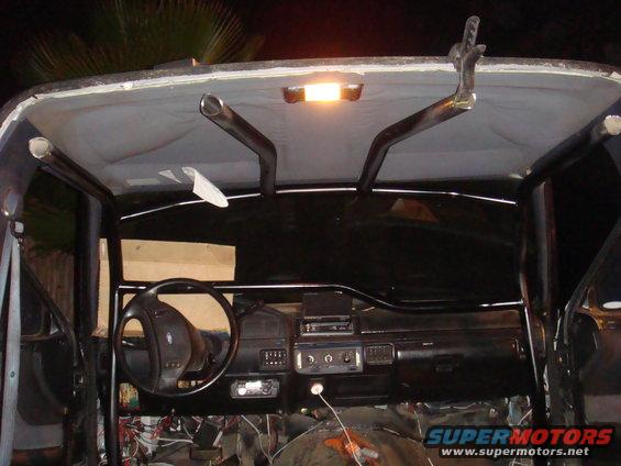 1992 Ford Bronco interior with roll cage, aftermarket stereo, and exposed wiring