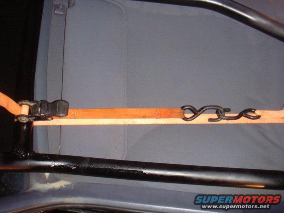 Interior view of a vehicle cage with an orange strap and ratchet mechanism