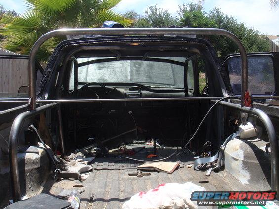Truck bed with custom roll cage installed. Interior visible, dashboard and seats are present