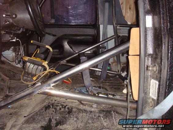 Vehicle interior with roll cage, seatbelt, and steering wheel visible