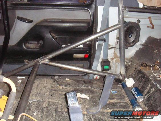 Interior view of a vehicle with a roll cage, seatbelts, and a speaker