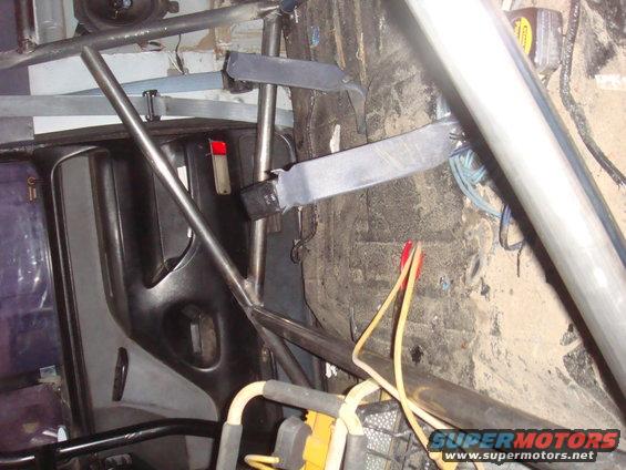 Interior view of a roll cage with seatbelt mounts and wiring
