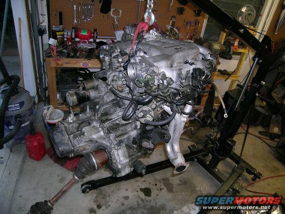 Engine assembly on hoist, V6 engine cover visible