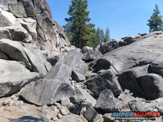 Rocky landscape with large boulders and trees under a clear blue sky