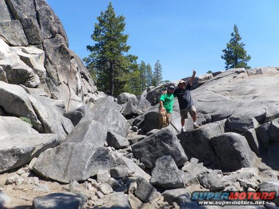 Two men on a rocky outcrop under a clear blue sky