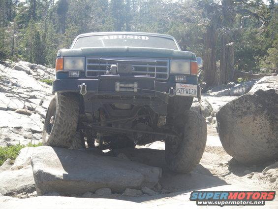 Ford F-Series truck on rocks, windshield sticker says 'ABUSED', California plate 5ZPW128